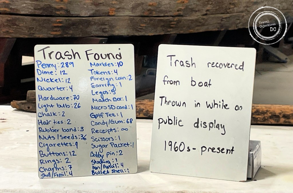 Whiteboard signs showing the items of trash thrown onto the Gunboat Philadelphia while it was on display.
